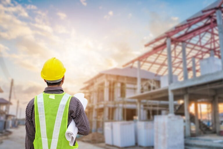 Young Professional Engineer In Protective Helmet And Blueprints